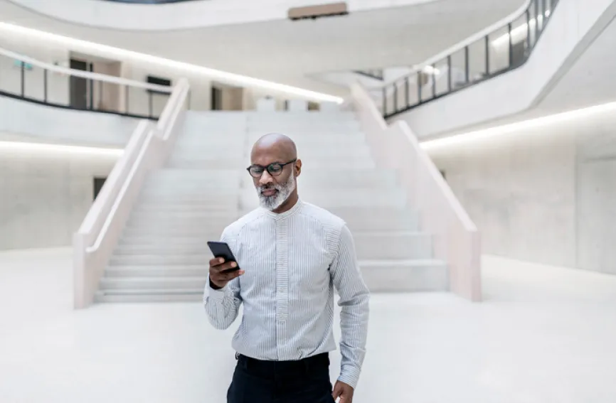 Businessman looking at his smartphone at the bottom of a dramatic staircase