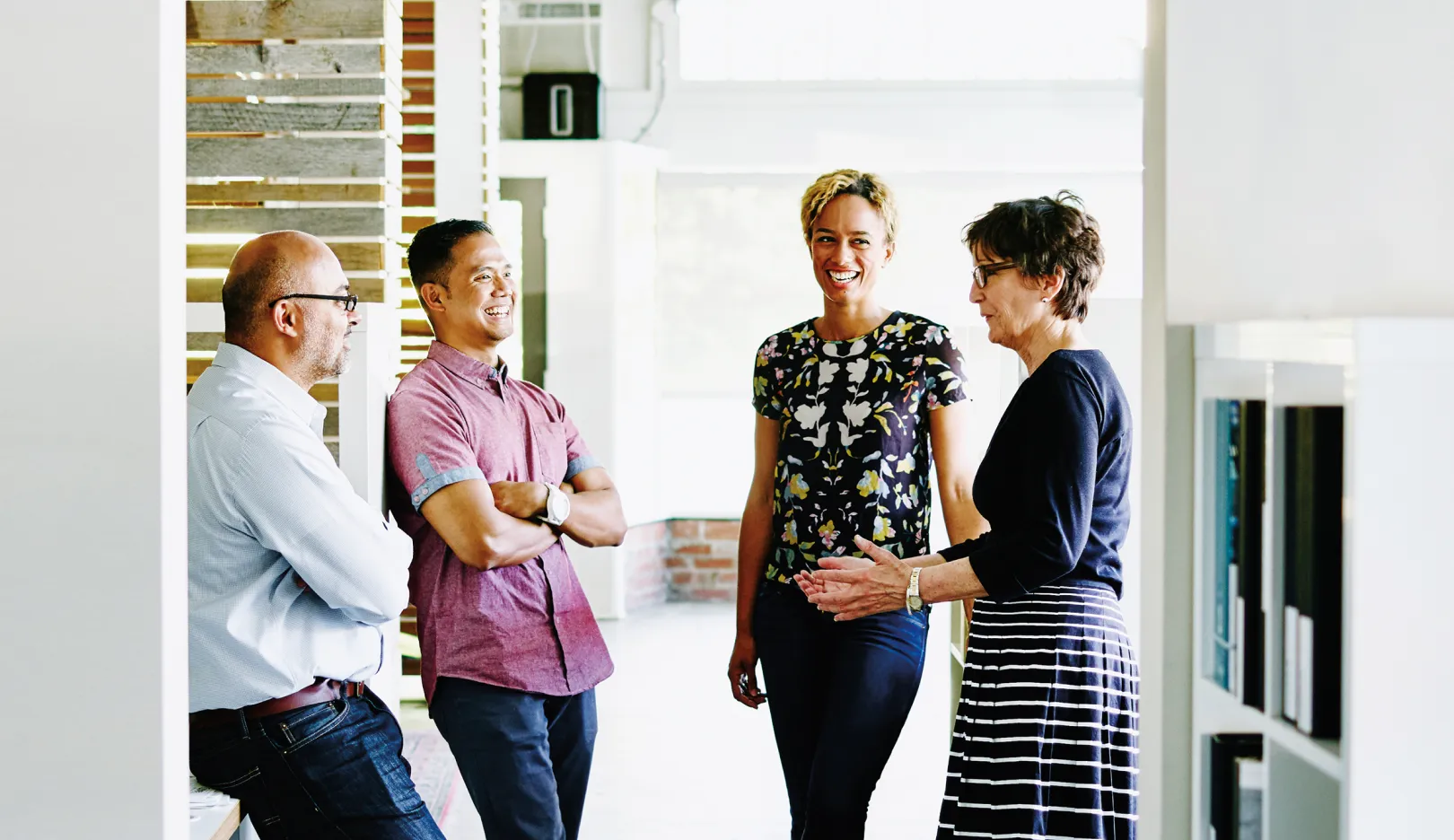 Colleagues standing in an open meeting area and sharing a humorous moment