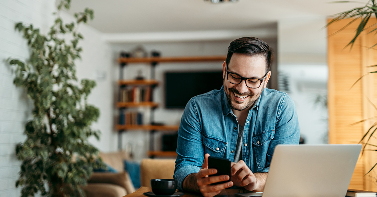 Man in his home looking down at his phone and smiling