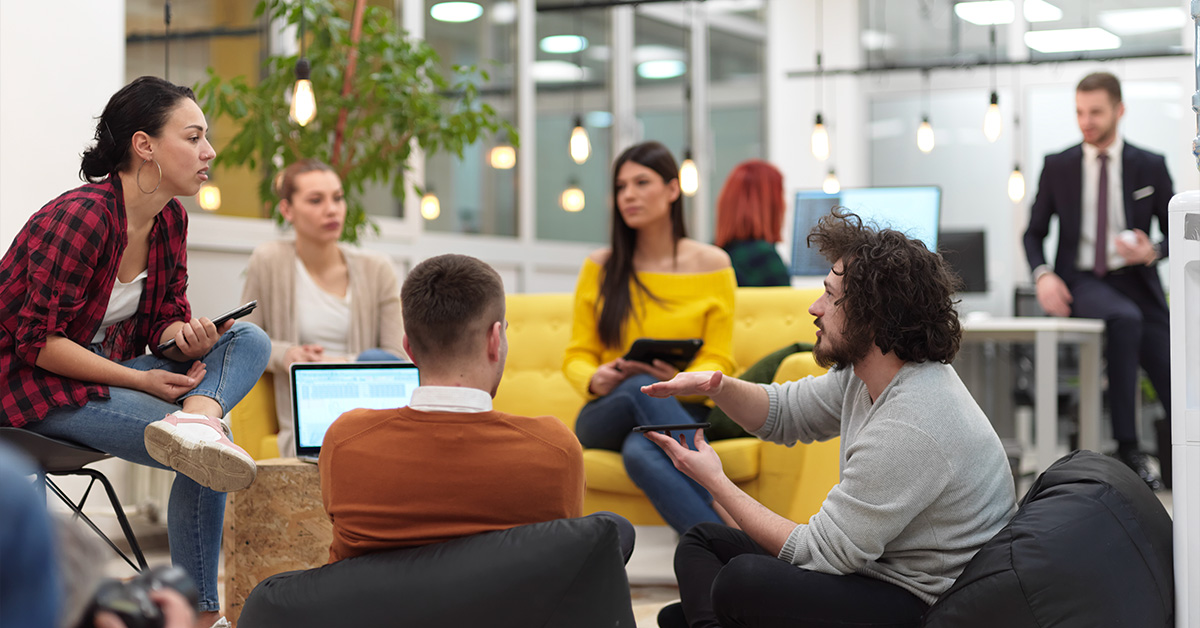 Five people sitting in an modern, open space collaborating on work.