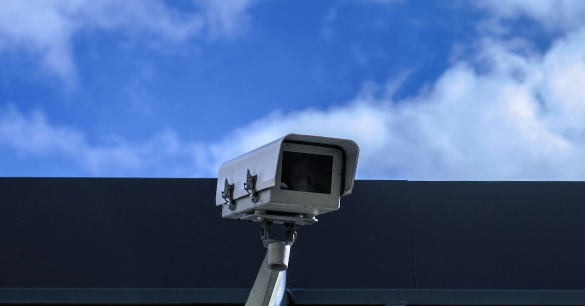 Security camera looks out in front of a background of clouds. 