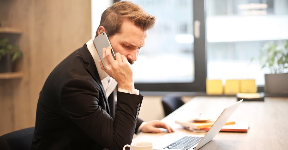 a man looks concerned while taking a work call on his mobile device