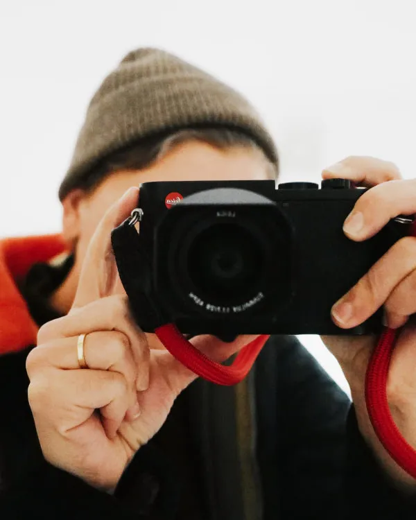 VSCO photographer taking a photo behind a Leica camera with red strap