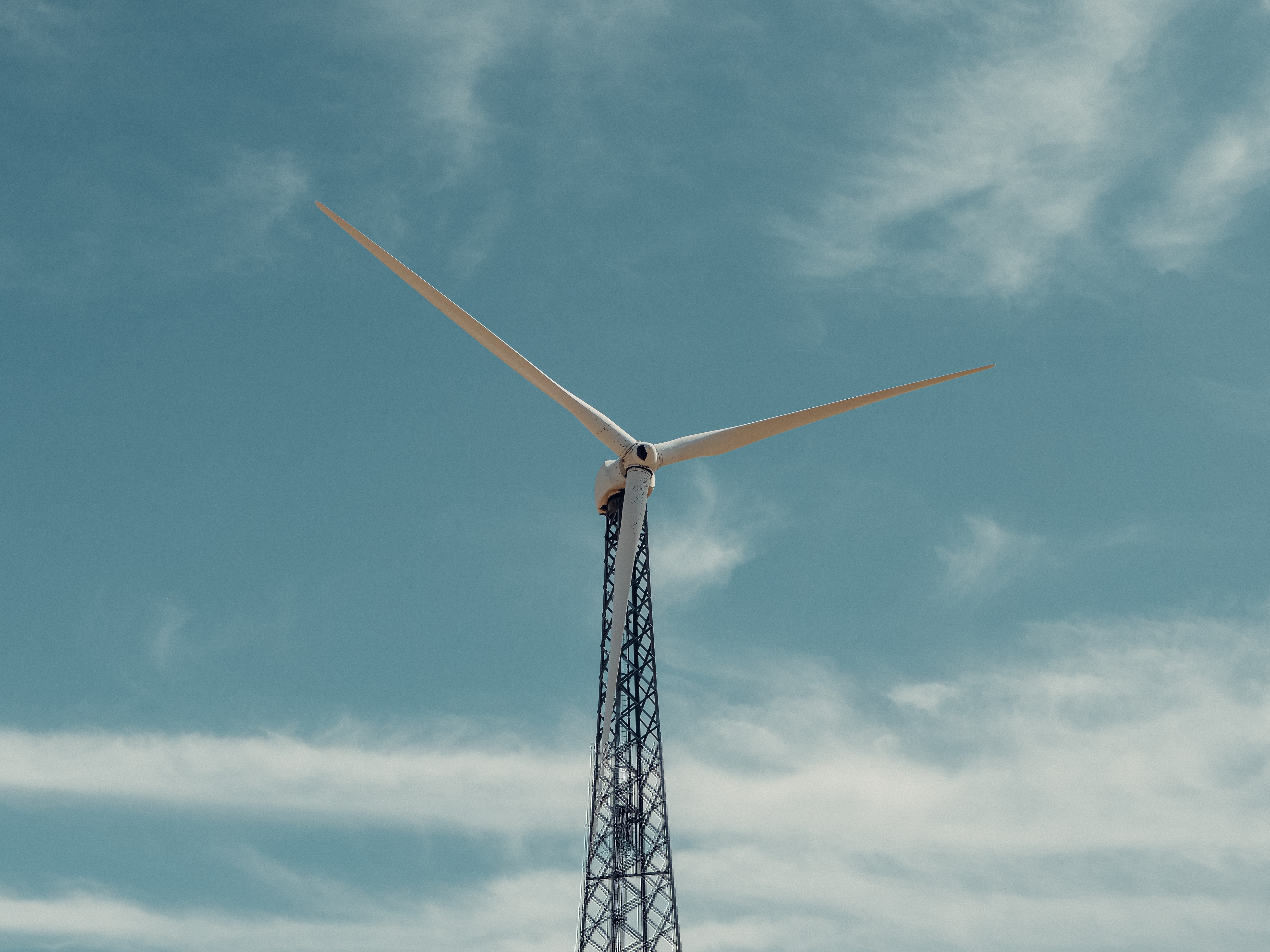 The top of a wind turbine in front of a blue, sunny sky