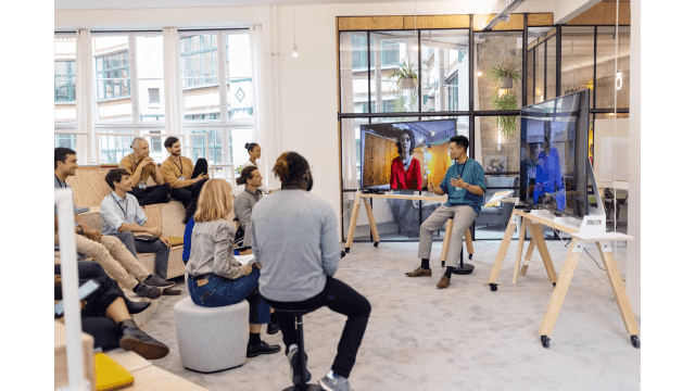 An informal meeting with video screens in a modern office space.