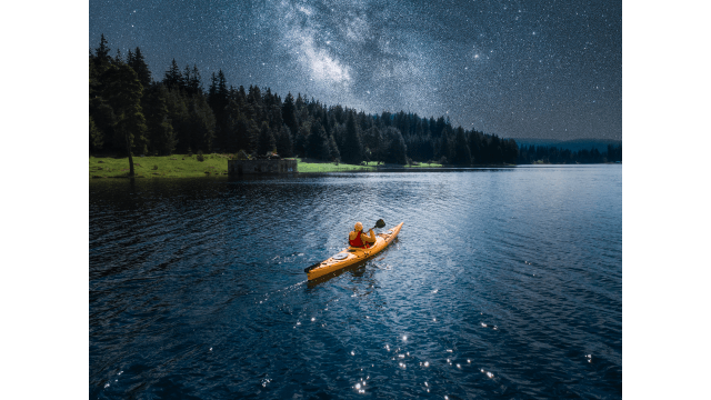 Drone point of view above woman with yellow kayak rowing and connecting with nature at night.