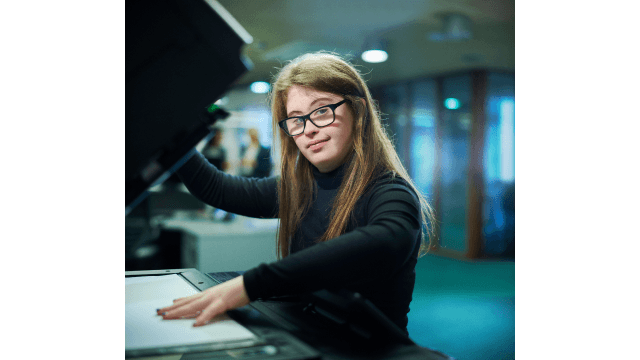 A young woman using a photocopier machine.