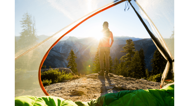 A woman taking in the view at sunrise while camping in the mountains.