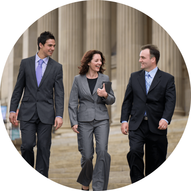 Two men and one woman in suites walking in front of government building