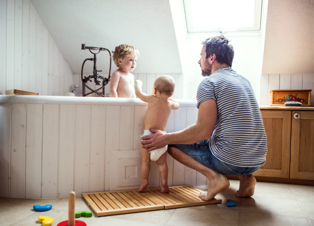 Father washing two toddlers in the bathroom at home.