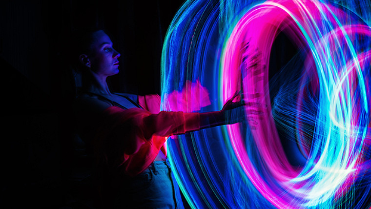 photographie claire d'une femme avec les bras étendus et des tourbillons de lumière