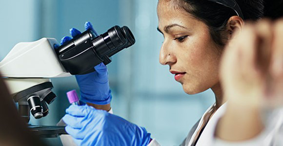 woman looking through a microscope