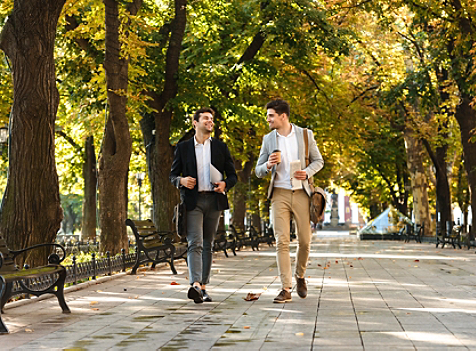 men walking in green park with coffee and laptop