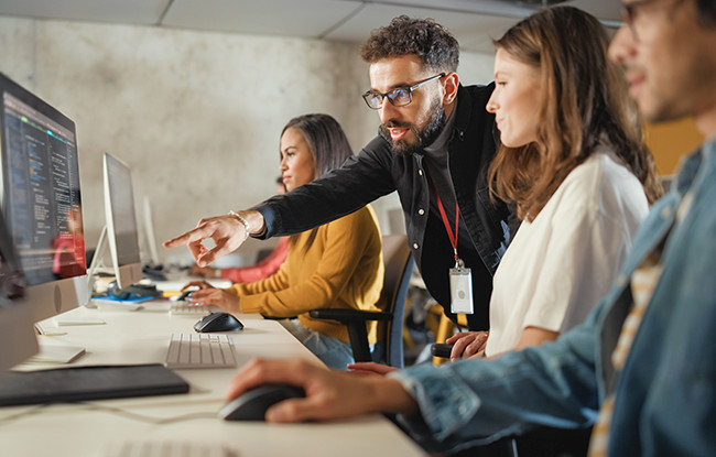 Man pointing to computer screen having a discussion with female colleague