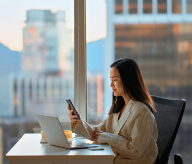 woman working at a desk holding a mobile