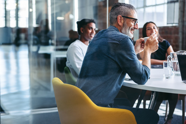 An employee cheerfully engaging with his team members in a meeting.