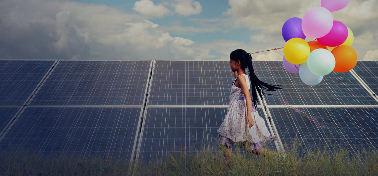 a girl running with balloons beside a solar panel