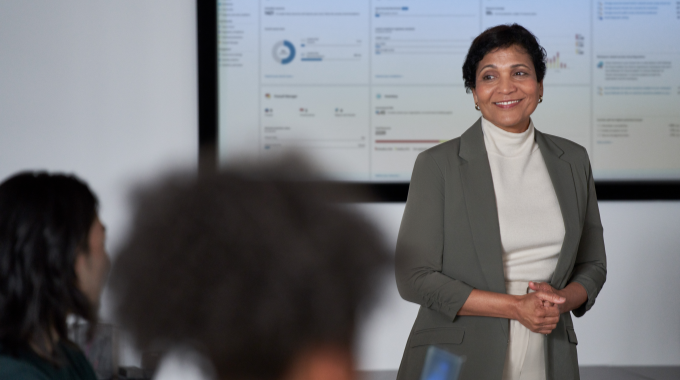 Female business leader presents to the board of executives in a conference room setting.