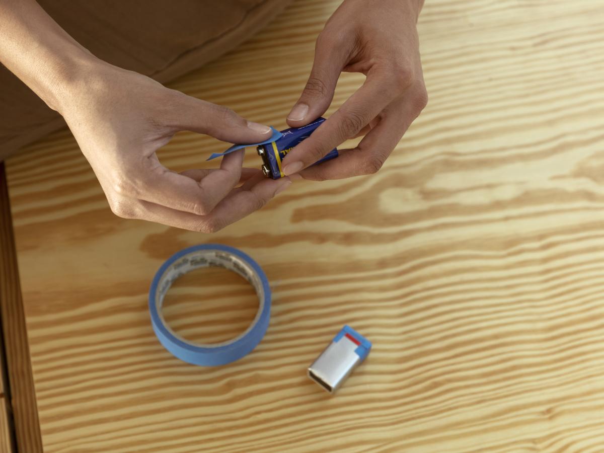 guy putting tape on empty 9V batteries