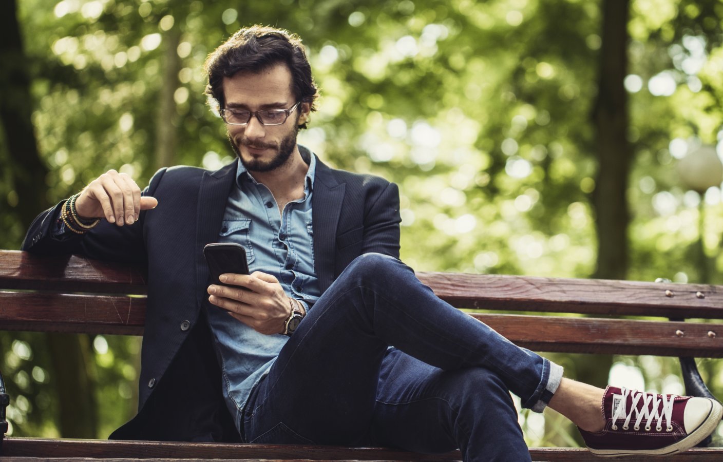 Chill guy using his phone sitting on a bench