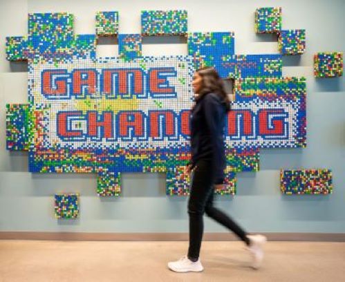 An AWS employee walks past the game changing wall in an AWS office.