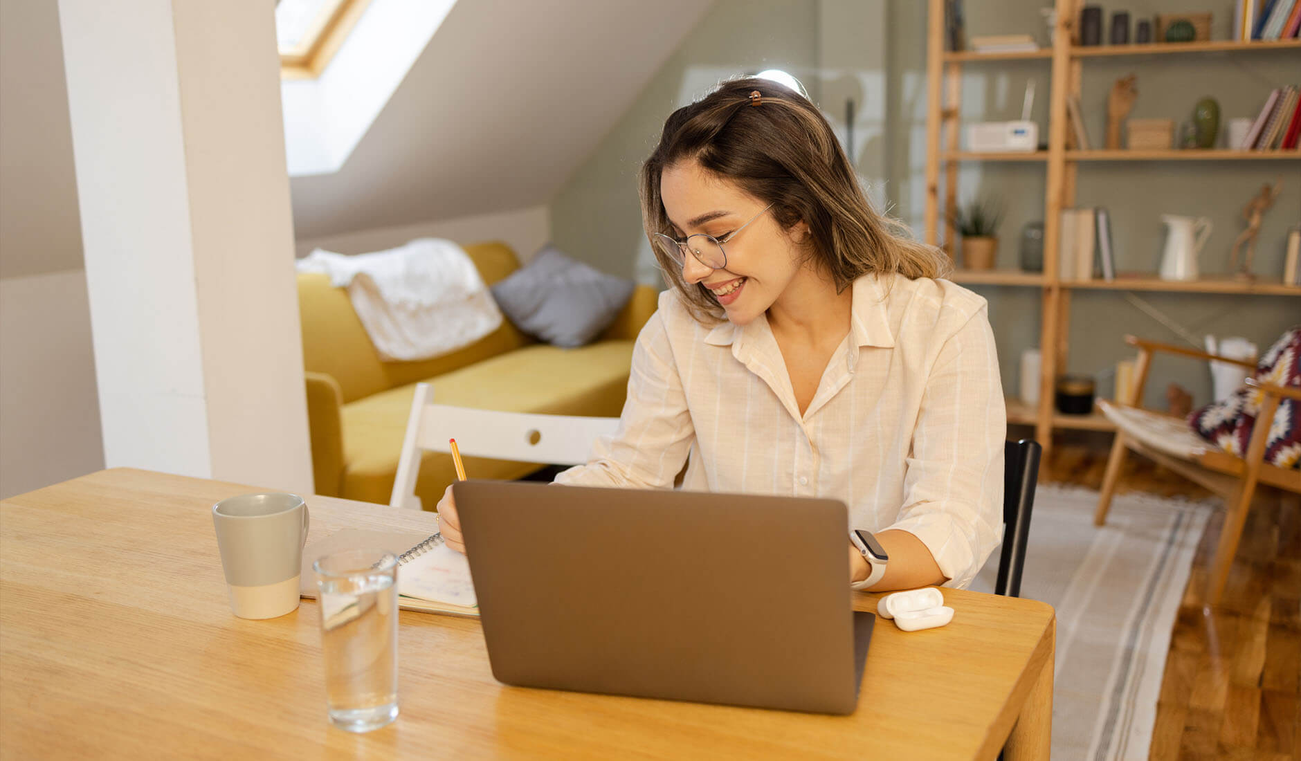 girl working on her computer and taking notes on paper