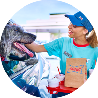 Sonic carhop petting a dog in a car while holding an order.