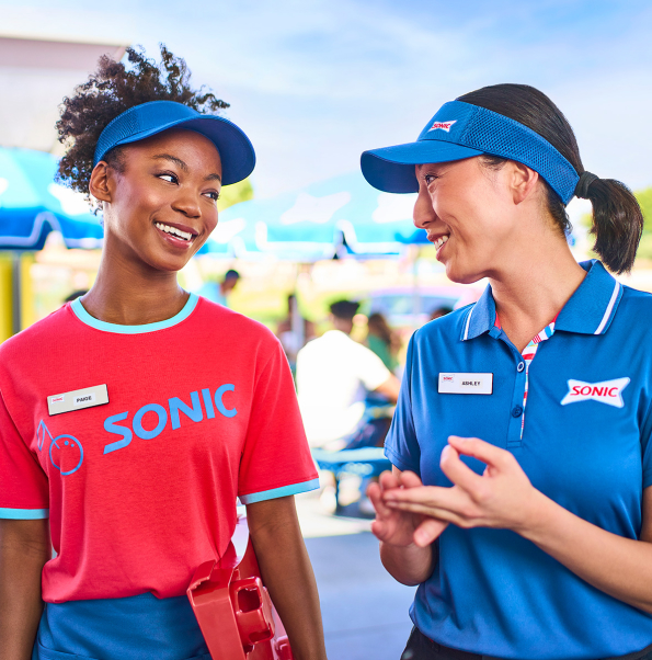 Two Sonic employees smiling and having a conversation.