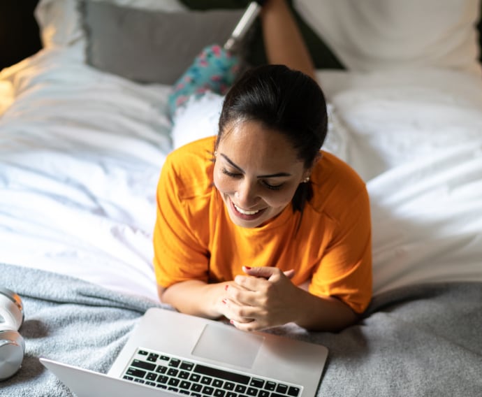 Frau im orangefarbenem Shirt, die im Bett liegt.