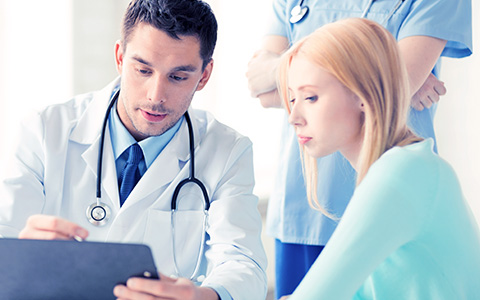 doctor holding clipboard while speaking with patient