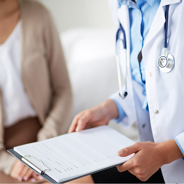 doctor holding clipboard while speaking with patient