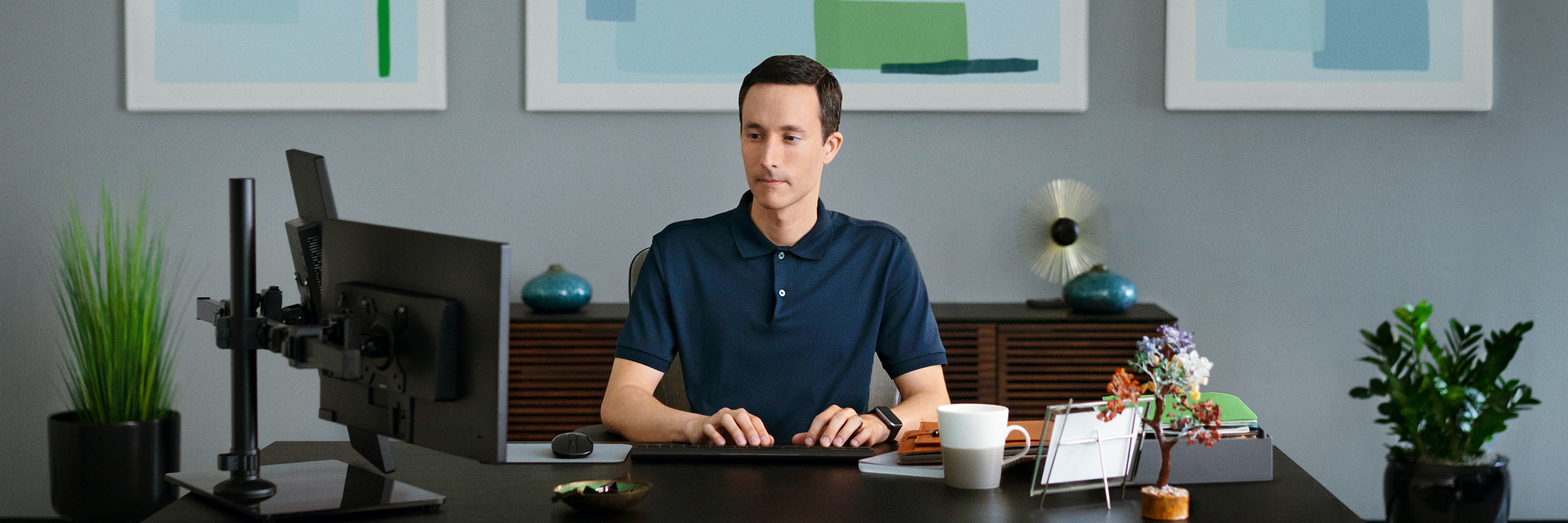 man in navy shirt typing at computer