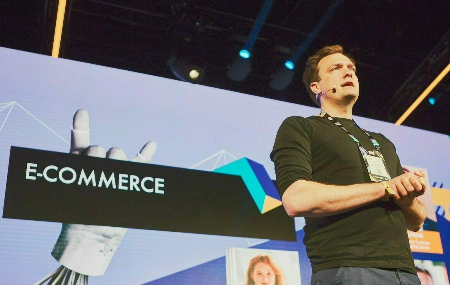 At the OMR Festival 2022, a man wearing a headset microphone stands in front of a large screen displaying the word "E-COMMERCE" during his presentation.