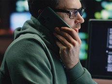 Man talking on cell phone surrounded by computers and data