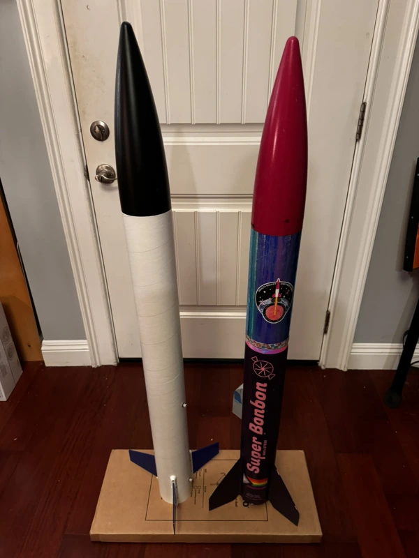 The completed blue, black, and white Fishhawk rocket standing next to a purple, chrome, and pink LOC IV rocket