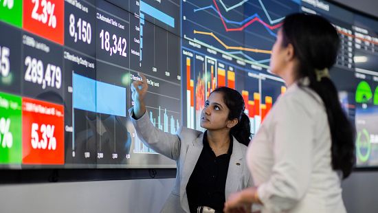 business people grouped around large computer display