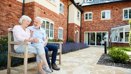 Senior couple seated outdoors in a long-term care community