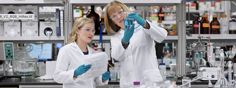 Two Ecolab experts examining a liquid in a beaker.