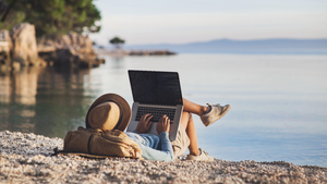 person lying on a beach while working on a laptop