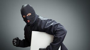 Thief in face mask stealing laptop computer