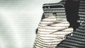 A person holding an iPhone lit up by a projector showcasing binary code