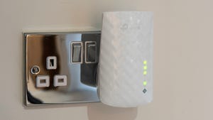 A TP-link wi-fi extender plugged into a wall socket