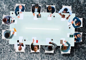 People sitting around boardroom table, viewed from above