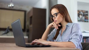 Young professional woman with glasses looking at laptop