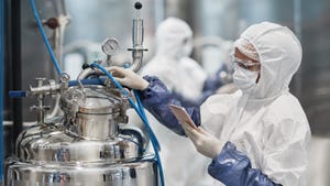 A worker wearing a protective suit while operating equipment at a modern chemical plant