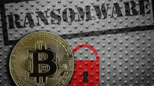 The word "ransomware" in black like it was stamped on and under it a red padlock next to a gold coin with the Bitcoin symbol on it 