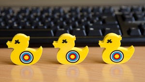 Three yellow plastic ducks with targets painted on them in front of a keyboard