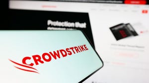 CrowdStrike logo on a phone screen with the website on a computer screen blurred out in the background