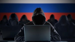 Rows of hooded figures beside laptops. The background behind them is the Russian flag