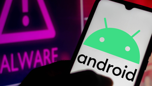 Shadowed hand holding a device with the word "Android" and green Google Android logo on the screen next to computer screen warning "malware"